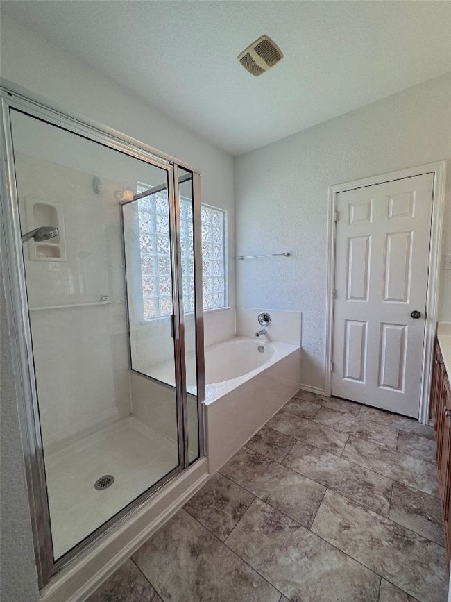 Bathroom featuring a garden tub, a stall shower, and vanity | Image 19