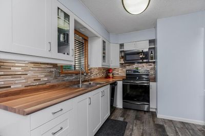 Kitchen with wood counters, white cabinetry, sink, and stainless steel appliances | Image 3