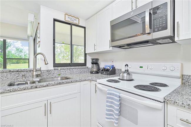 Kitchen with stainless steel microwave, electric stove, a sink, and white cabinetry | Image 4
