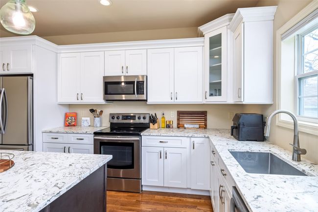 Kitchen with white cabinets, stainless steel appliances, a sink, dark wood-type flooring, and glass insert cabinets | Image 11