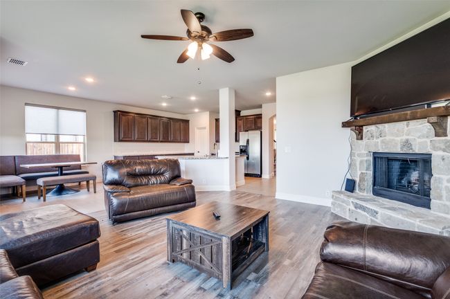 Living room with a ceiling fan, a stone fireplace, light wood-type flooring, and recessed lighting | Image 6