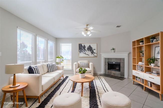 Living room featuring ceiling fan, light tile patterned floors, and a tiled fireplace *Virtually Staged* | Image 5