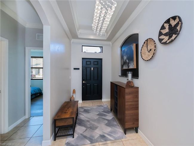 Entryway featuring light tile patterned flooring, a raised ceiling, arched walkways, visible vents, and ornamental molding | Image 18