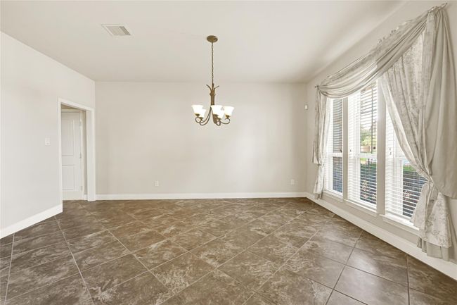 Across the hall, the formal dining room balances elegance with ease, with tall windows nearly reaching the floor and elegant tiling underfoot that ties into the rest of the main level. | Image 9