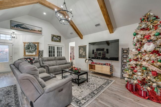 Living room featuring high vaulted ceiling, french doors, an inviting chandelier, beamed ceiling, and light hardwood / wood-style floors | Image 6