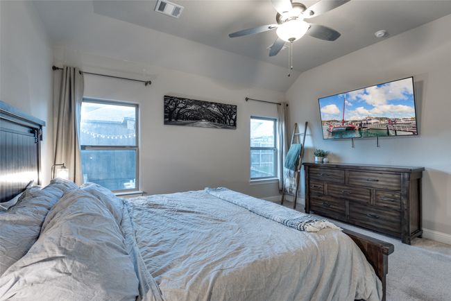 Carpeted bedroom featuring lofted ceiling, baseboards, visible vents, and ceiling fan | Image 15