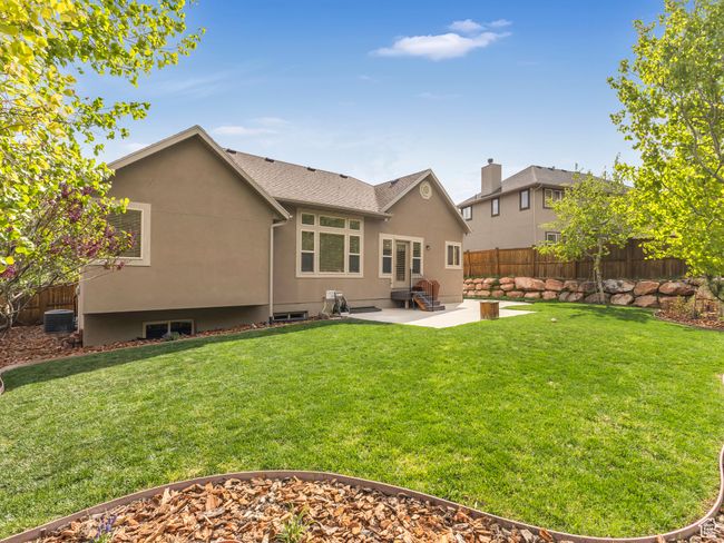 Rear view of property featuring a patio area, central AC unit, entry steps, stucco siding, and a shingled roof | Image 8