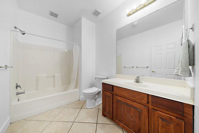 Clean bathroom with a shower-tub combination and a large vanity | Image 30