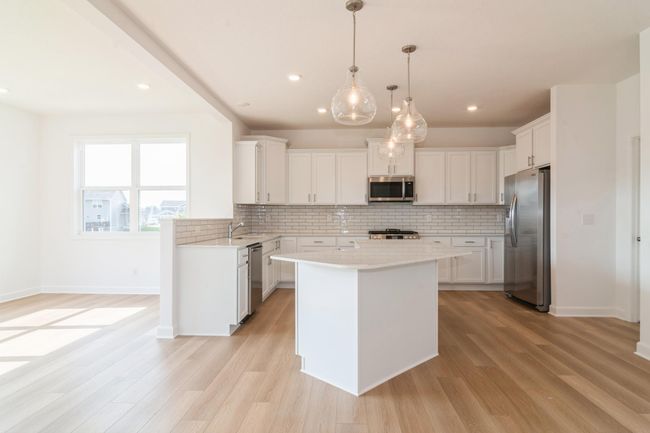 (Photo of a decorated model, actual homes finishes will vary) This stunning kitchen features a large center island, quartz countertops, LVP floors, stainless appliances and more! | Image 5