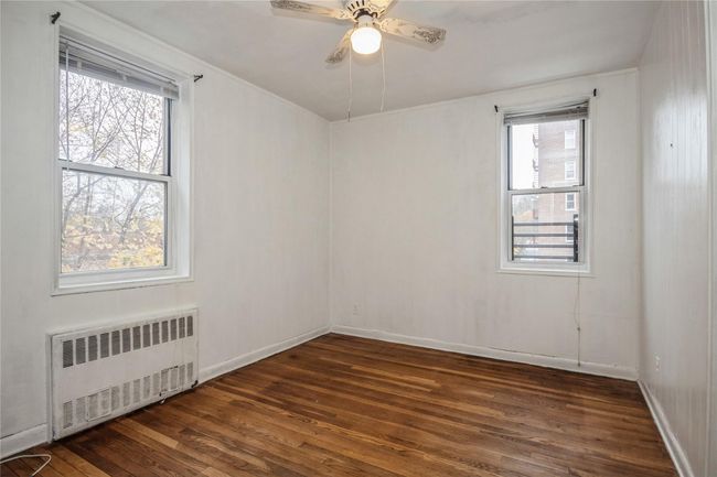 Unfurnished room featuring radiator heating unit, dark wood-style flooring, and ceiling fan | Image 11