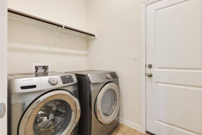 Laundry room featuring washing machine and dryer, light tile patterned floors, and baseboards | Image 27