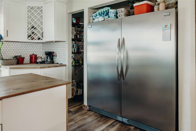 Kitchen featuring stainless steel fridge, butcher block counters, white cabinetry, and dark wood-style floors | Image 12