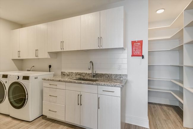 Clothes washing area with a sink, light wood-type flooring, cabinet space, and washing machine and dryer | Image 10