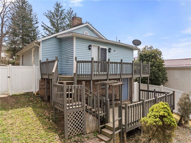 Rear view of property featuring a chimney, fence, and a deck | Image 20