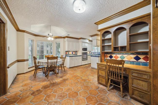 The large dining nook features saltillo tile flooring and a built-in wooden desk. | Image 13