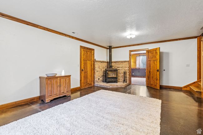 Living room with ornamental molding, a wood stove, and a textured ceiling | Image 33