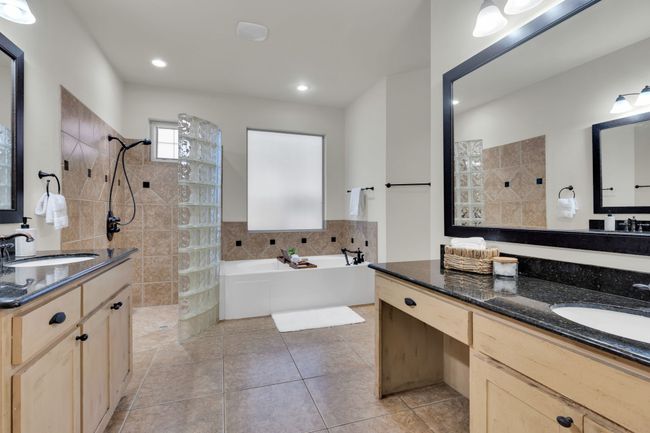 Full bathroom with walk in shower, a bathtub, two vanities, tile walls, and tile patterned flooring | Image 17