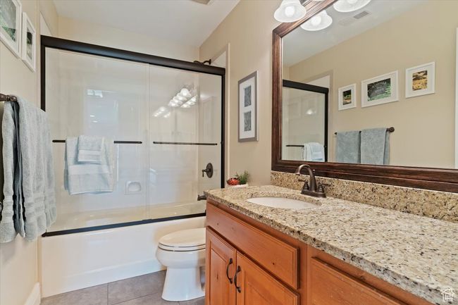 Full bath featuring tile patterned flooring, visible vents, vanity, toilet, and shower / bath combination with glass door | Image 39