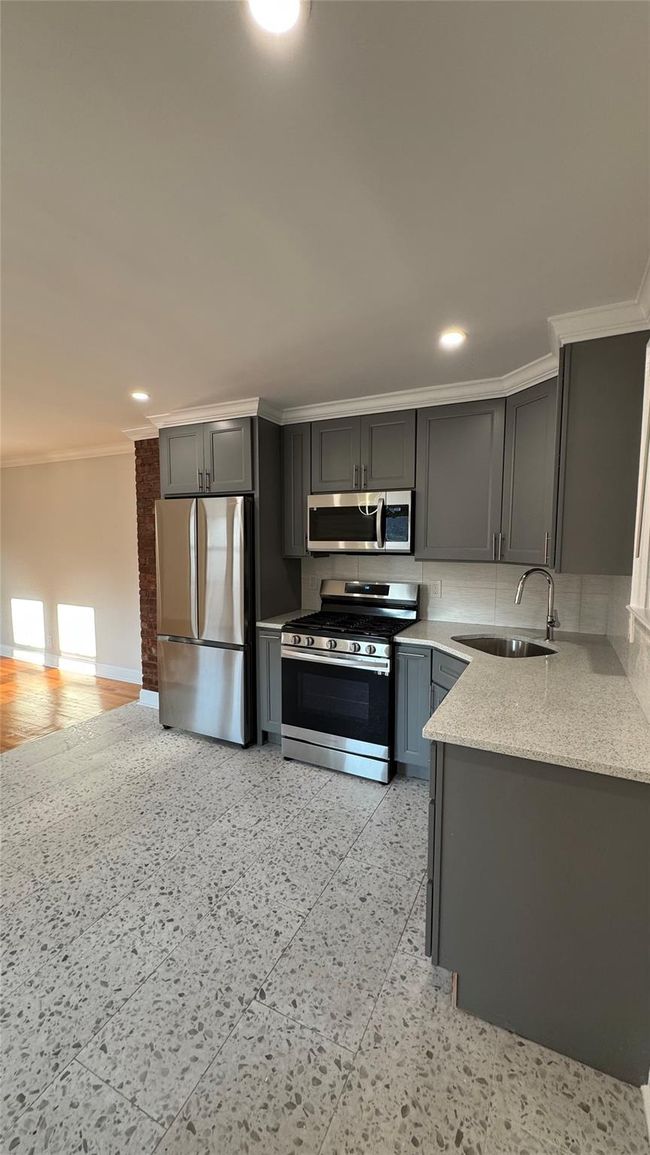 Kitchen with appliances with stainless steel finishes, crown molding, light stone counters, gray cabinetry, and recessed lighting | Image 9