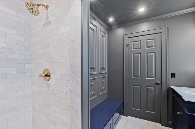 Bathroom featuring a tile shower, crown molding, vanity, and wood-type flooring | Image 27