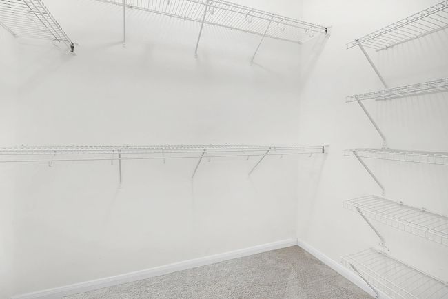 Primary closet with multiple hanging rods and shelves for storage. | Image 20