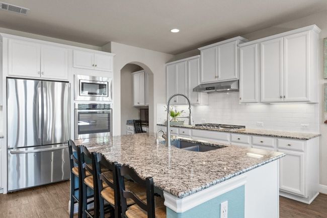 Kitchen featuring appliances with stainless steel finishes, under cabinet range hood, arched walkways, recessed lighting, and dark wood finished floors | Image 11