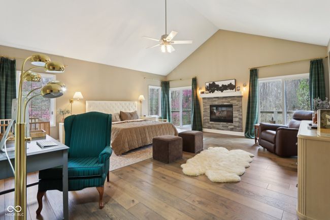 bedroom with hardwood / wood-style floors, high vaulted ceiling, a ceiling fan, and a stone fireplace | Image 26