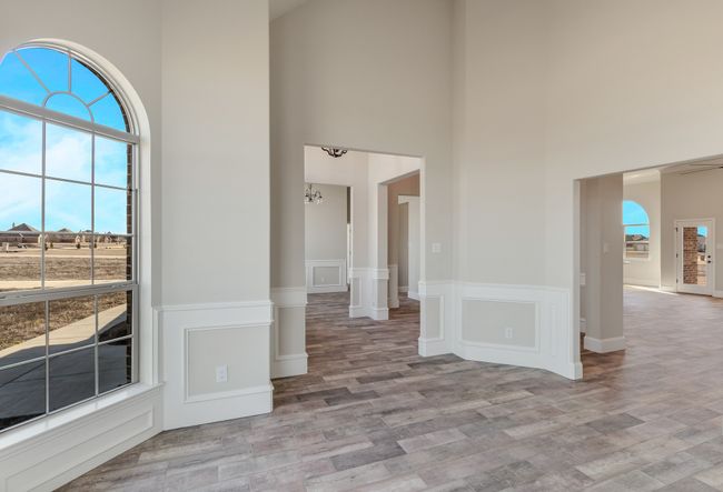 Spare room featuring a high ceiling, light wood-style flooring, and a wainscoted wall | Image 11