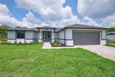 View of front of house featuring a front yard, a garage, and central air condition unit | Image 1