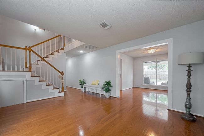 From the entry, looking through the Formal Dining room you look out to the porch and backyard pool! The stairs leading to the 4 bedrooms is on the left. | Image 8
