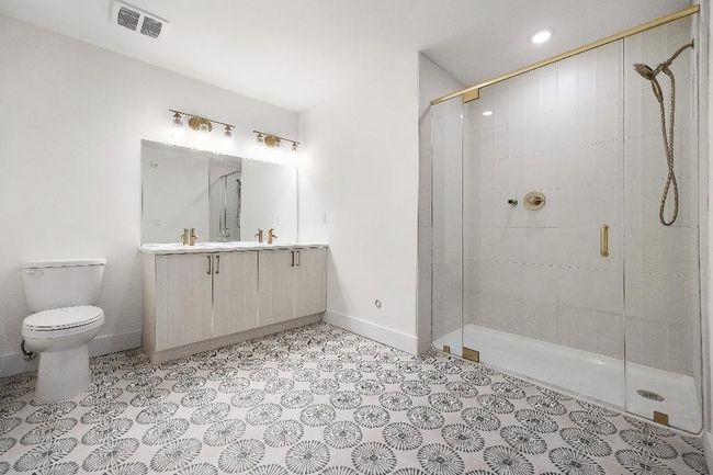 Bathroom featuring a stall shower, toilet, tile patterned floors, vanity, and baseboards | Image 23