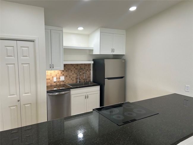 Kitchen featuring backsplash, open shelves, appliances with stainless steel finishes, white cabinets, and a sink | Image 4