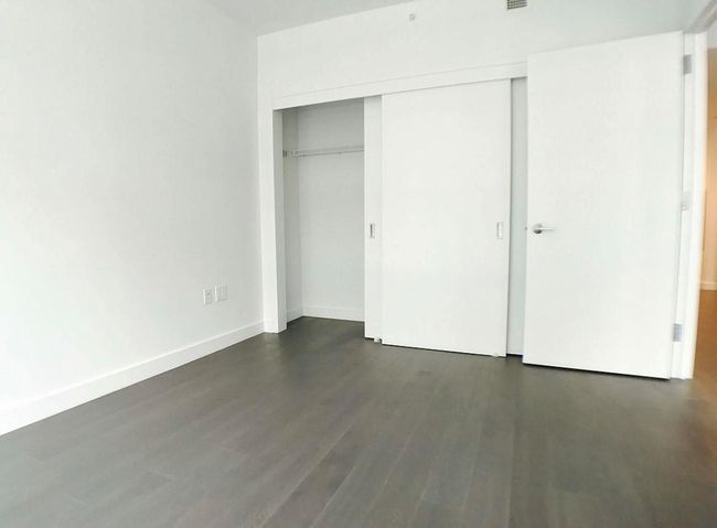 Unfurnished bedroom with dark wood-style floors and a closet | Image 6