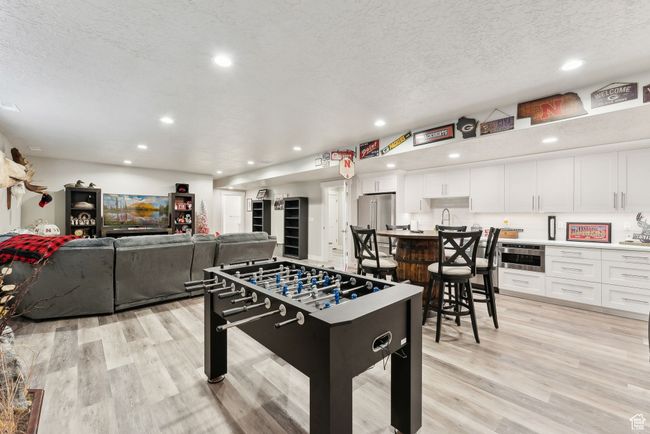 Recreation room featuring recessed lighting, a textured ceiling, a sink, and light wood-type flooring | Image 33