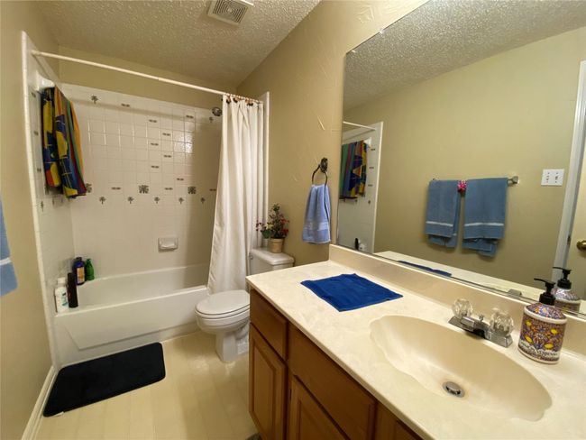 Full bathroom featuring shower / tub combo with curtain, vanity, a textured ceiling, and toilet | Image 33