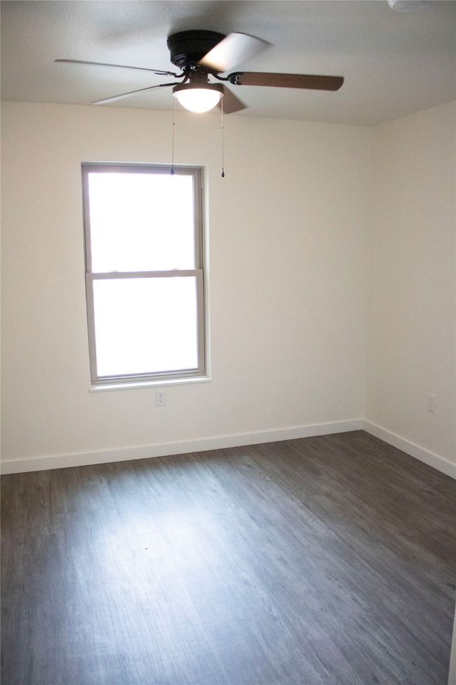 Spare room with dark wood finished floors, baseboards, and a ceiling fan | Image 6