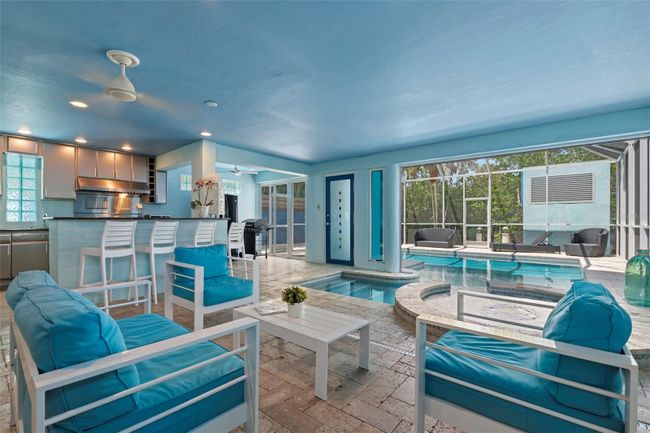 The first level features an indoor/outdoor swimming pool and spa, screened-in lounge area and full outdoor kitchen with stainless appliances and gas range making it the perfect place for family fun and entertaining. | Image 28