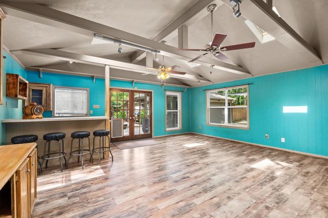 This spacious, open room features vibrant turquoise walls, vaulted ceilings with exposed beams, and skylights for natural light. | Image 20
