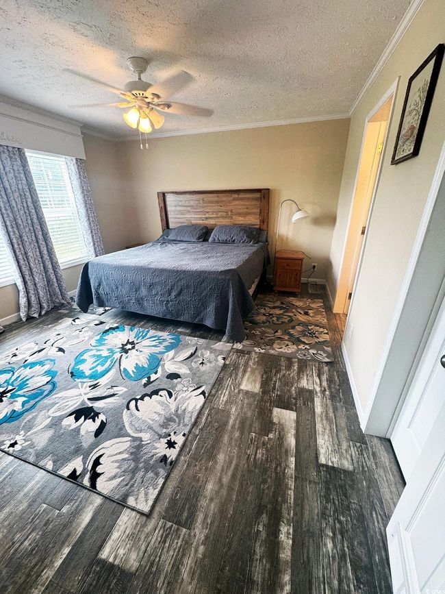 Bedroom with a textured ceiling, wood finished floors, crown molding, and a ceiling fan | Image 20