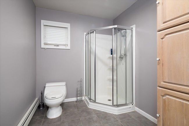 Bathroom with a baseboard heating unit, tile patterned floors, and a shower stall | Image 14