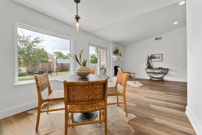 Dining space with vaulted ceiling, a brick fireplace, light wood-style flooring, and recessed lighting | Image 5