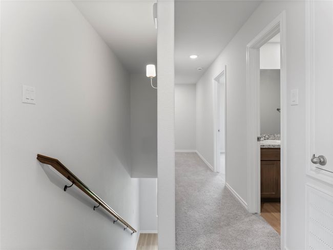 Cozy carpeted upstairs hallway leading to spacious rooms and a bathroom. | Image 10