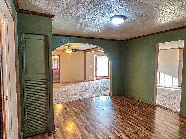 Unfurnished room featuring arched walkways, crown molding, and wood finished floors | Image 10