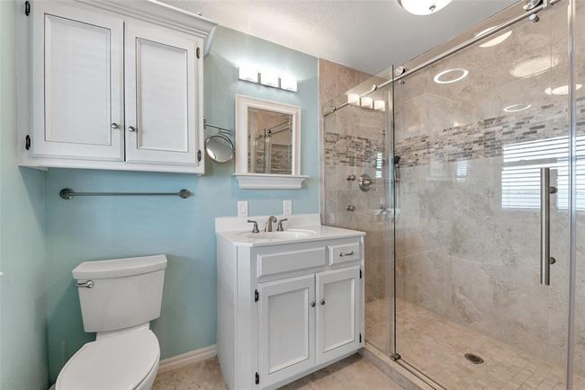 Enjoy the spa-like feel of this beautifully updated ensuite featuring a walk-in tile shower with glass enclosure, white vanity, and linen cabinetry for added storage. Clean lines and soft tones create a calming retreat. | Image 25