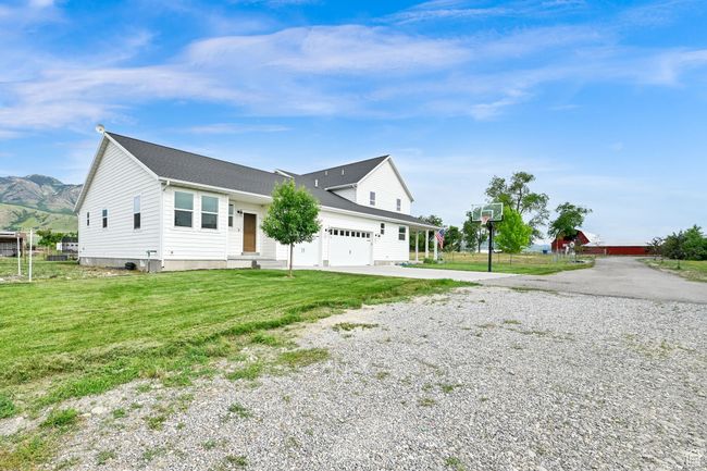 View of home's exterior featuring gravel driveway, a garage, a lawn, a shingled roof, and a mountain view | Image 44