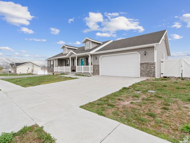 View of front facade featuring a porch, a garage, concrete driveway, and stone siding | Image 24
