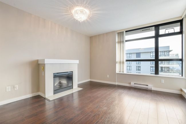 Unfurnished living room with baseboard heating, dark wood-style floors, a fireplace with flush hearth, and a chandelier | Image 4