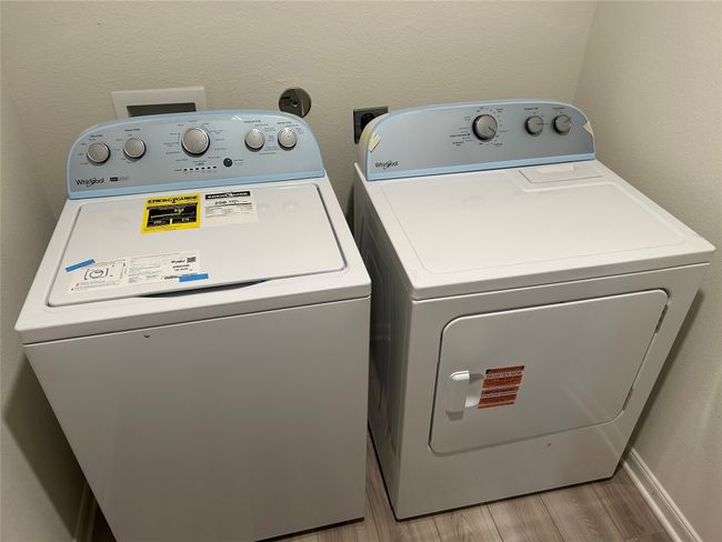 Laundry area featuring laundry area, washing machine and dryer, light wood-type flooring, and a textured wall | Image 10