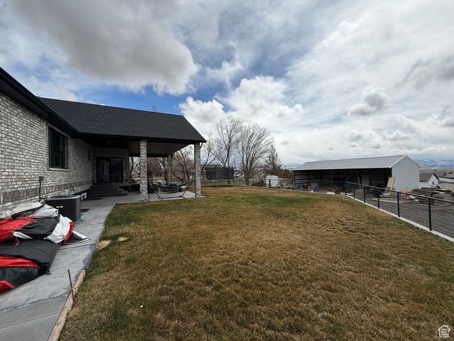 View of yard with cooling unit, an outdoor structure, fence, and a patio area | Image 26