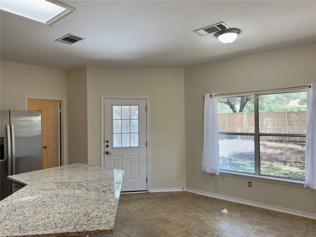 Kitchen featuring healthy amount of natural light, stainless steel refrigerator with ice dispenser, and light stone counters | Image 9